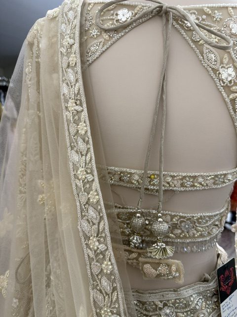 Ivory net bridal lehenga, blouse back with beaded strap panels and tasselled tie cords