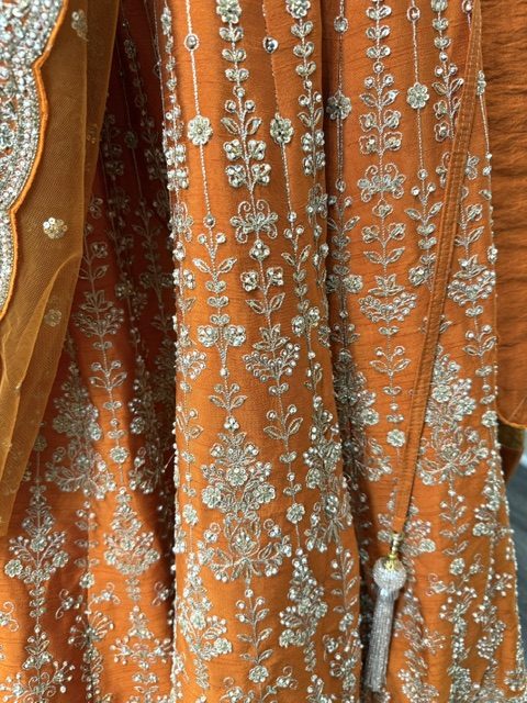 Orange raw silk bridal lehenga, silver floral vine embroidery on the skirt