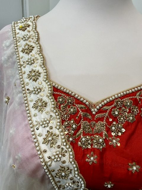 Red raw silk bridal lehenga, sweetheart neckline with pearl edging and gold zardozi