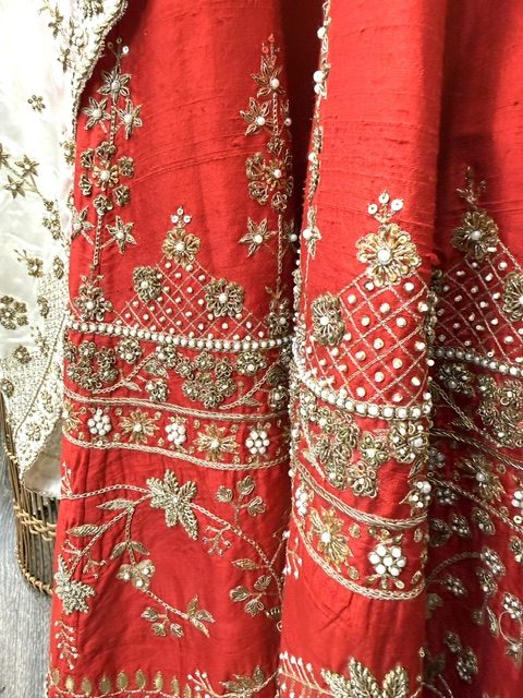 Red raw silk bridal lehenga, close view of the pearl and gold trellis work with the dupatta border