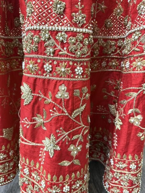 Red raw silk bridal lehenga, gold zardozi and pearl embroidery on the skirt panels