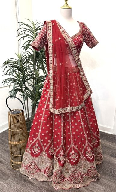 Red raw silk bridal lehenga, front view showing the embroidered blouse and scalloped hem border