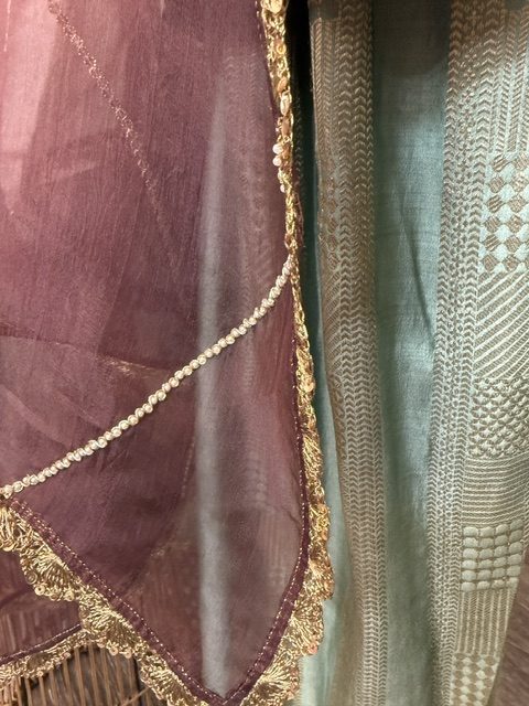 Close view of the plum organza dupatta border beside the woven farsi salwar