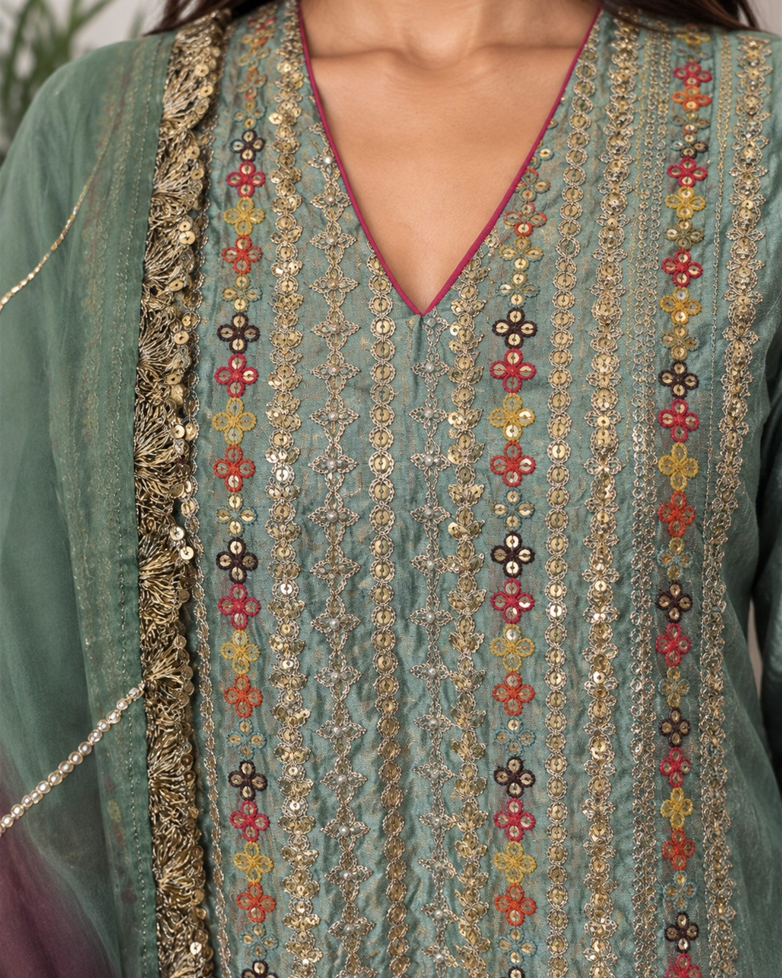 Close view of the kurta placket, vertical bands of gold sequin work with coral, mustard and plum flowers